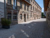 a view of a bricked side walk in an industrial building, with windows on two sides of the walkway