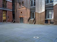 the courtyard is empty of people and steps, with trees in the corner of the building