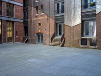 the courtyard is empty of people and steps, with trees in the corner of the building