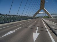 a truck driving across a bridge near a street corner near buildings and a bridge with many cables