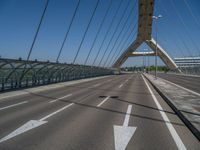 a truck driving across a bridge near a street corner near buildings and a bridge with many cables