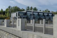 a long concrete fence is next to the building and street corner with multiple parked cars in it