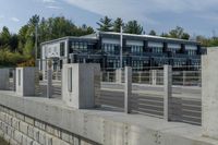 a long concrete fence is next to the building and street corner with multiple parked cars in it