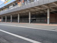 a bus is going by the side of a bus station and some cars are sitting nearby