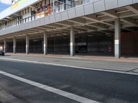 a bus is going by the side of a bus station and some cars are sitting nearby