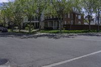 an empty street with a stop sign next to houses on the side of it that are under a few trees