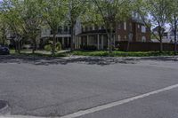 an empty street with a stop sign next to houses on the side of it that are under a few trees