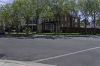 an empty street with a stop sign next to houses on the side of it that are under a few trees