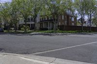 an empty street with a stop sign next to houses on the side of it that are under a few trees