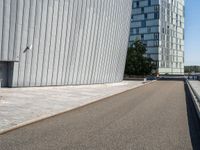 a skateboarder with an open road near large buildings with glass windows on the side