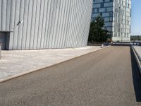 a skateboarder with an open road near large buildings with glass windows on the side