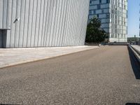 a skateboarder with an open road near large buildings with glass windows on the side