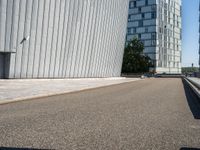 a skateboarder with an open road near large buildings with glass windows on the side