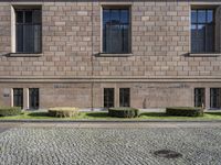 the entrance of a large building with brick walls and several windows in front of it