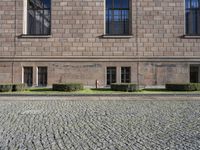 the entrance of a large building with brick walls and several windows in front of it