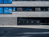 a large window in a building in front of a parking lot with the word pier 6 written on it