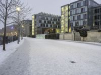 snow has fallen on the ground and trees near the buildings at dusk in front of a bench