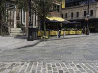 a street corner that has tables set up on it and a bench in front of the building