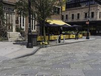 a street corner that has tables set up on it and a bench in front of the building