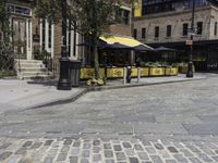 a street corner that has tables set up on it and a bench in front of the building