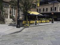 a street corner that has tables set up on it and a bench in front of the building