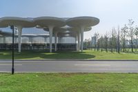 an architecturely designed building that is on the side of the street in front of a field with grass