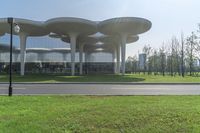 an architecturely designed building that is on the side of the street in front of a field with grass