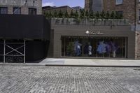 the facade of a store has some clothes on display outside it and bicycles on the sidewalk in front of the building