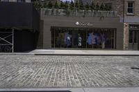 the facade of a store has some clothes on display outside it and bicycles on the sidewalk in front of the building