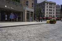 a view of a brick street with shops and patio seatings on either side of it