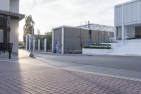 a person riding a skate board down the sidewalk near a building, with a light pole