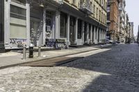 two benches are lined up along the side of a street in an alley by the sidewalk