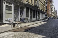 two benches are lined up along the side of a street in an alley by the sidewalk