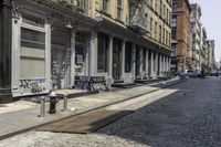 two benches are lined up along the side of a street in an alley by the sidewalk