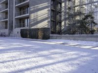 an apartment complex near buildings with snow on the ground and bikes parked next to it