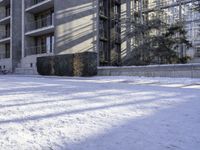 an apartment complex near buildings with snow on the ground and bikes parked next to it