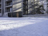 an apartment complex near buildings with snow on the ground and bikes parked next to it