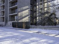 an apartment complex near buildings with snow on the ground and bikes parked next to it