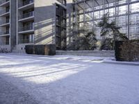 a person standing in the snow outside an office building in winter time, with one foot stuck in the ground