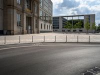 a empty street with a building in the background and a fence around it, leading to the parking lot