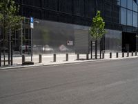 an empty street in front of a large building with glass panels on it and trees