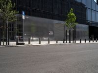 an empty street in front of a large building with glass panels on it and trees