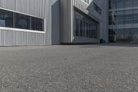 the side of a warehouse building next to a bicycle racket and garbage can on a concrete ground