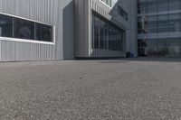 the side of a warehouse building next to a bicycle racket and garbage can on a concrete ground