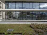 the exterior is completely covered with glass and lots of grass on the side of the road