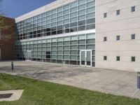 a building with large windows near the grass outside the building is made from concrete and has some glass on it