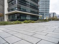 an empty brick sidewalk outside of a tall building with a few windows on it and a sign