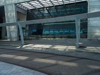 a man walking down a walkway next to tall buildings with glass walls and a walkway