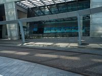 a man walking down a walkway next to tall buildings with glass walls and a walkway