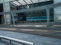 a man walking down a walkway next to tall buildings with glass walls and a walkway